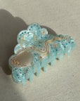 A 10cm celestial-themed acetate hair clip in light blue with a moon motif with rhinestone accent