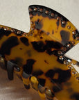 Tortoiseshell hair clip with rhinestone embellishments on a beige background