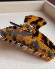 Tortoiseshell patterned hair clip with rhinestones on a light fabric background