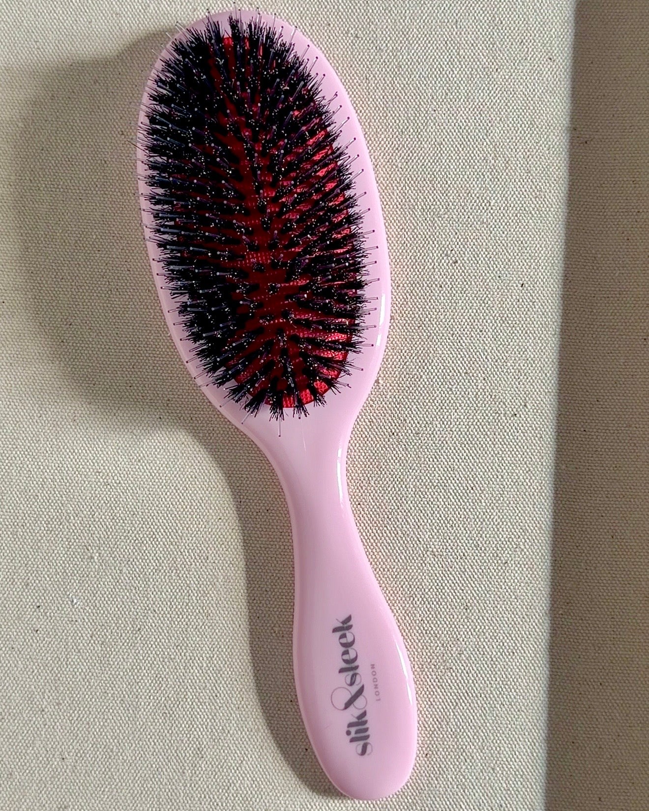 Pink hairbrush with  mixed boar and nylon bristles for smoothing and styling background - Slik &amp; Sleek London professional haircare