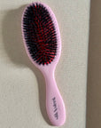 Pink hairbrush with  mixed boar and nylon bristles for smoothing and styling background - Slik & Sleek London professional haircare