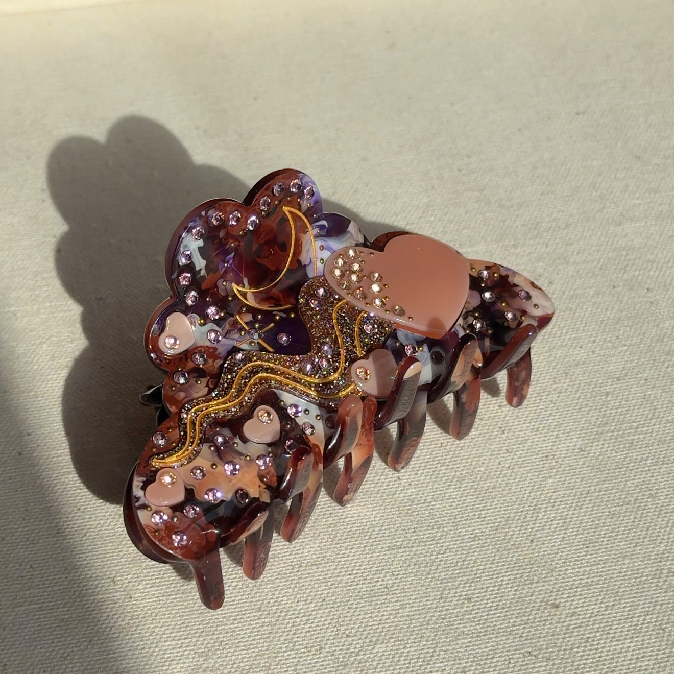 A 10cm celestial-themed acetate hair clip in burgundy with a moon motif with rhinestone accent