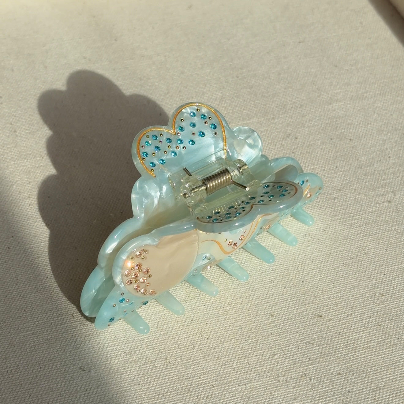 A 10cm celestial-themed acetate hair clip in light blue with a moon motif with rhinestone accent