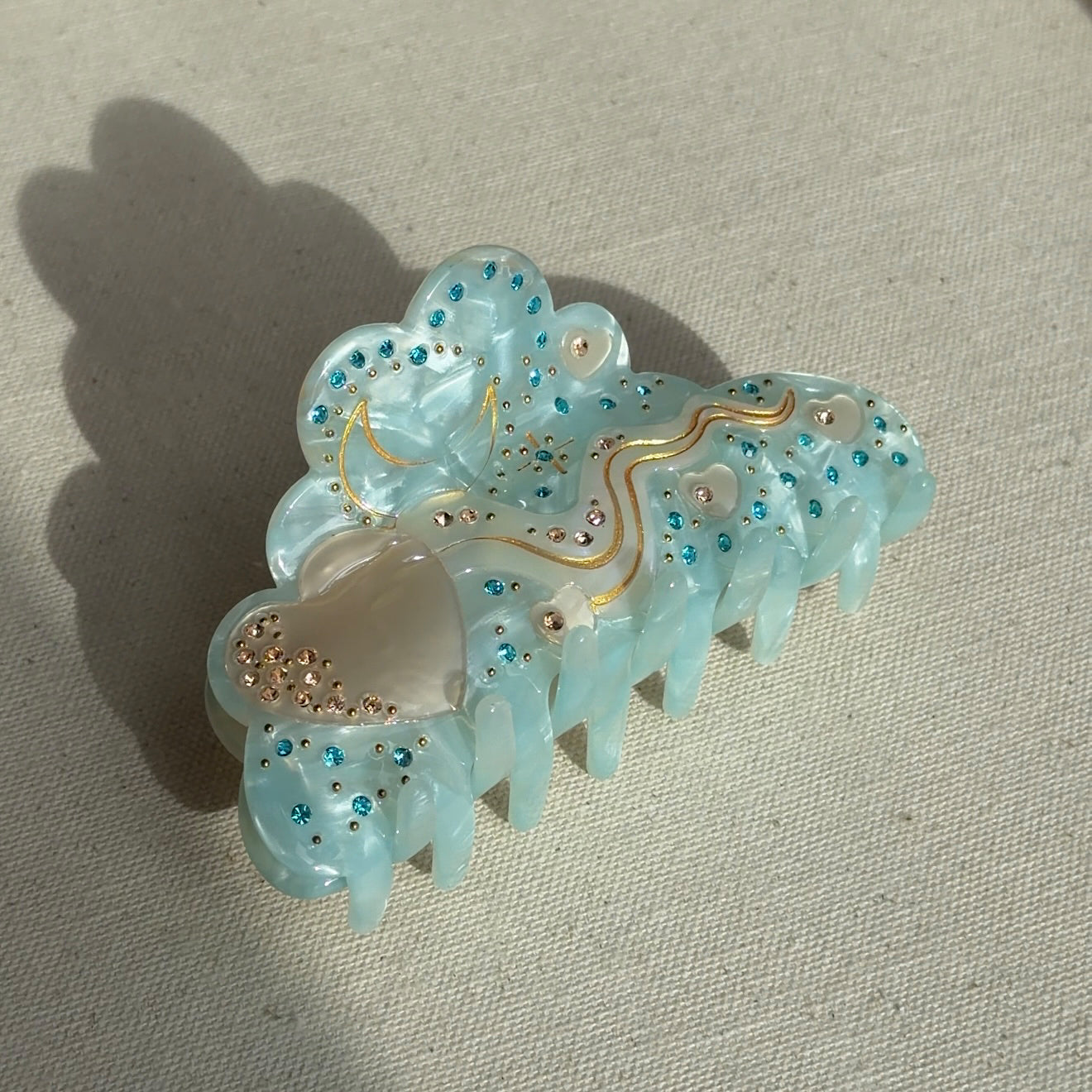 A 10cm celestial-themed acetate hair clip in light blue with a moon motif with rhinestone accent