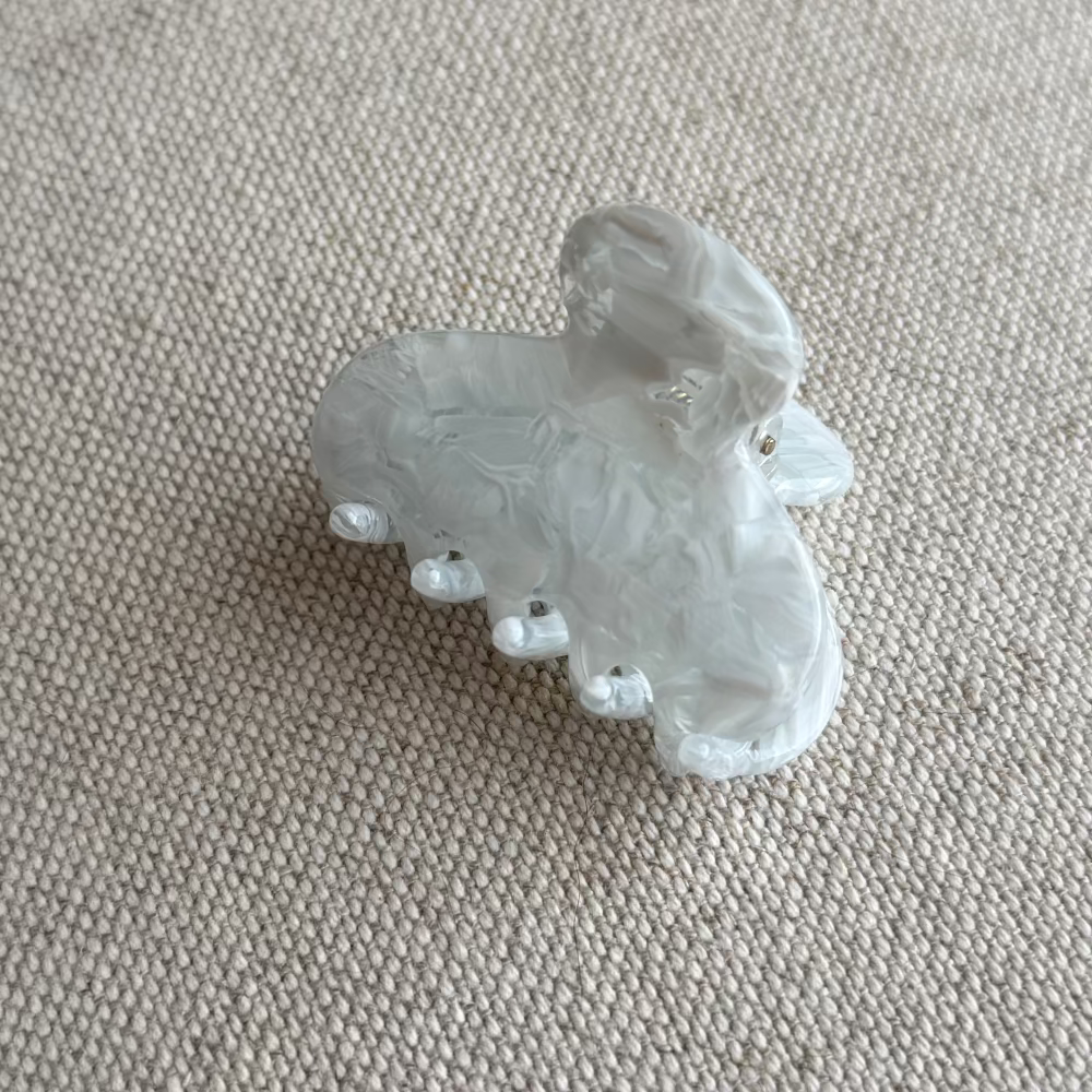 Clear acetate hair clip on a textured beige surface