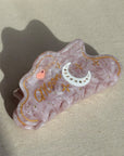 A 10cm celestial-themed acetate hair clip in pink with a moon motif with rhinestone accent