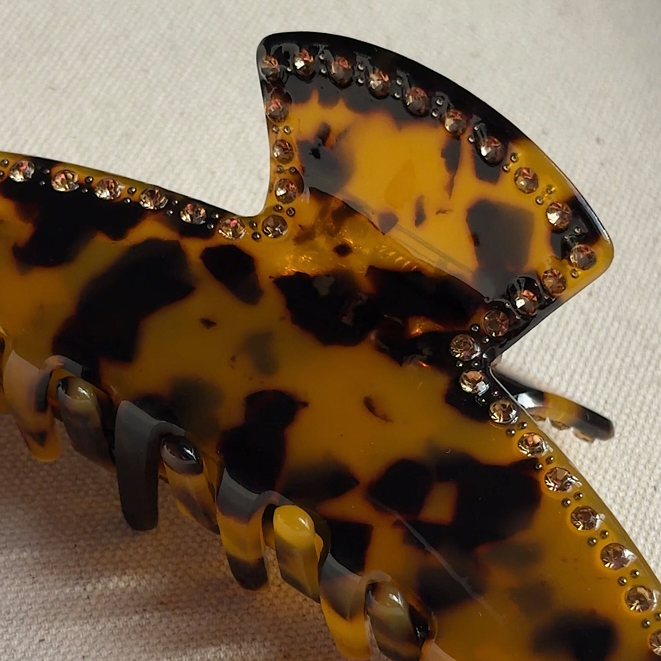 Tortoiseshell hair clip with rhinestone embellishments on a beige background